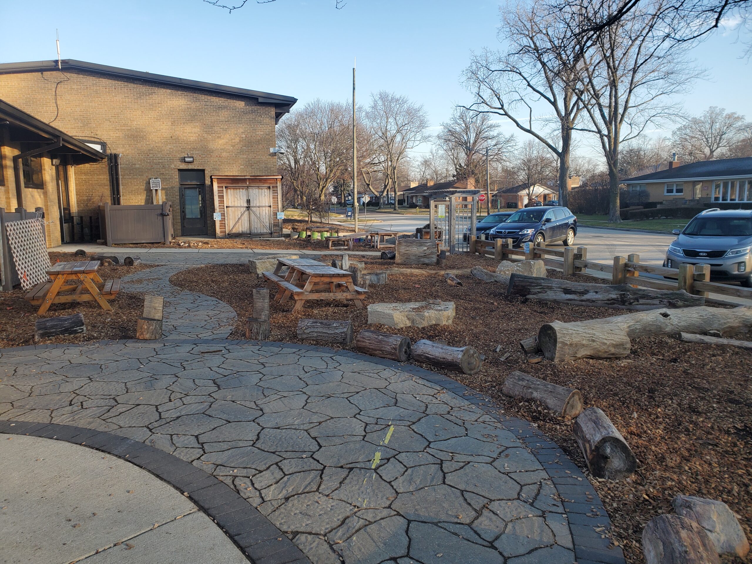 courtyard of the Wildwood Nature Center with picnic tables and log benches, woodchips, and lined with hardscaping