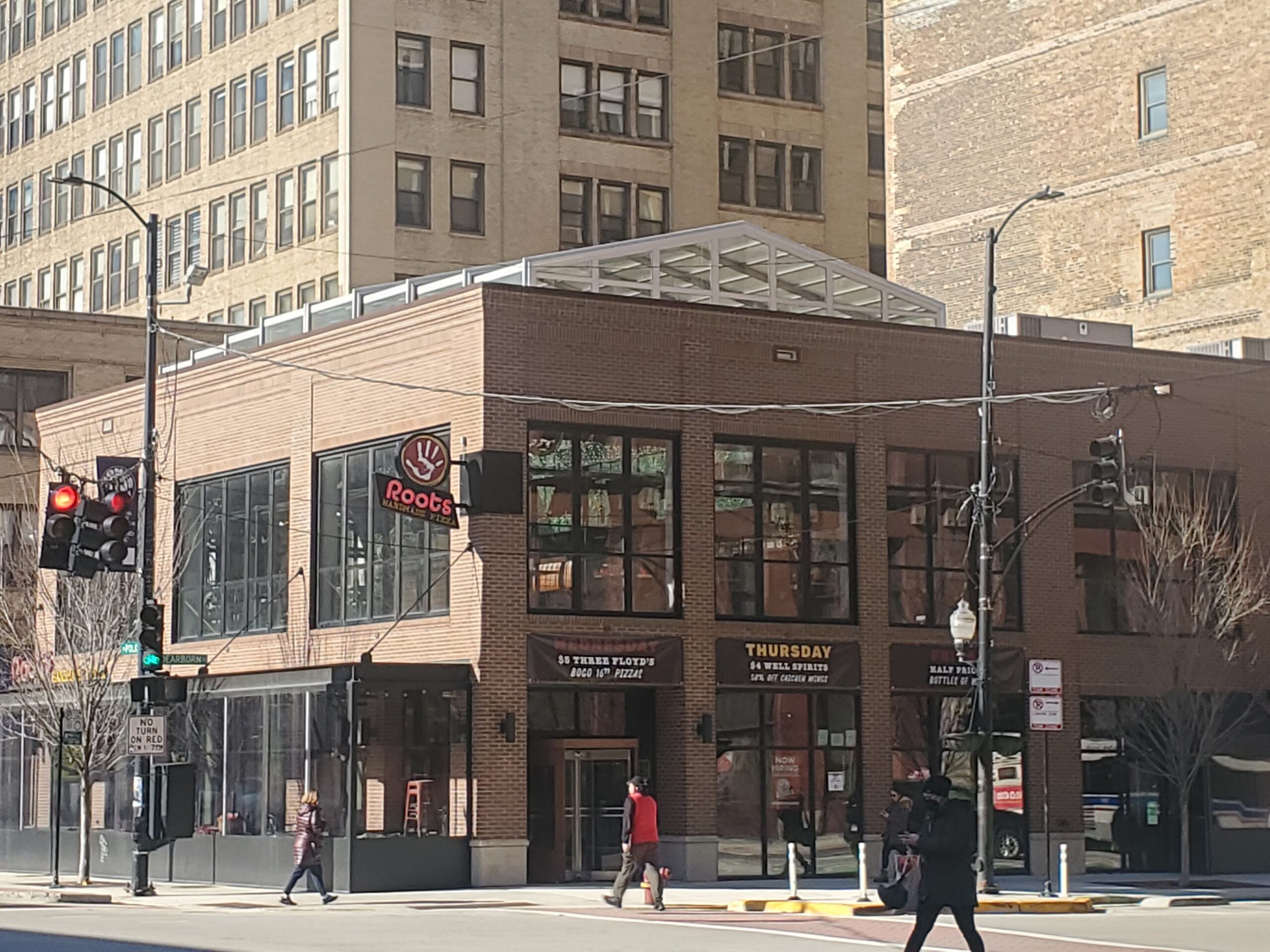 shot of a downtown pizza shop from across the street with people walking all around